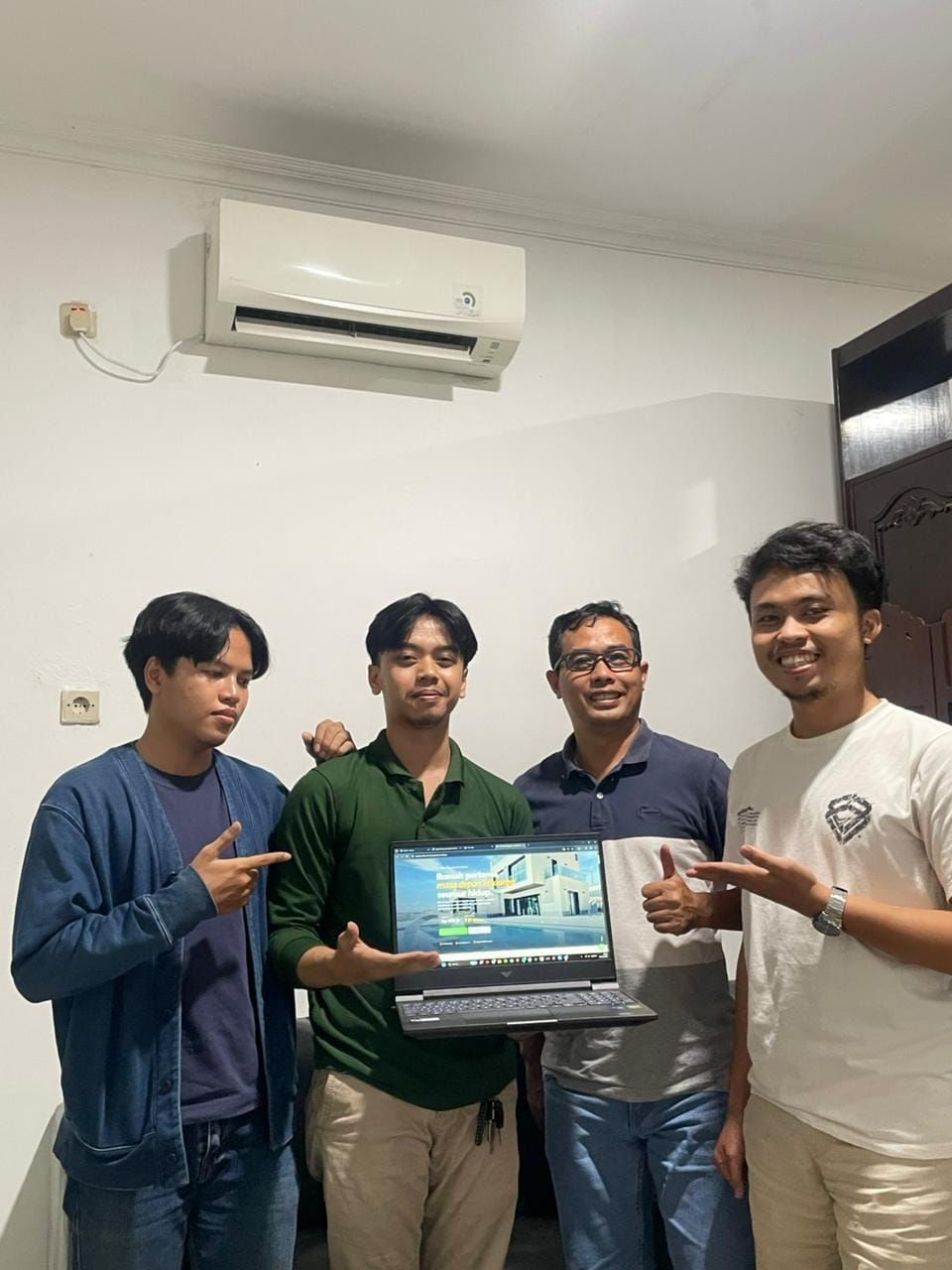 Fadal bersama dua rekan dan klien Rumah Asri berpose di dalam ruangan, memegang laptop yang menampilkan website Rumah Asri.